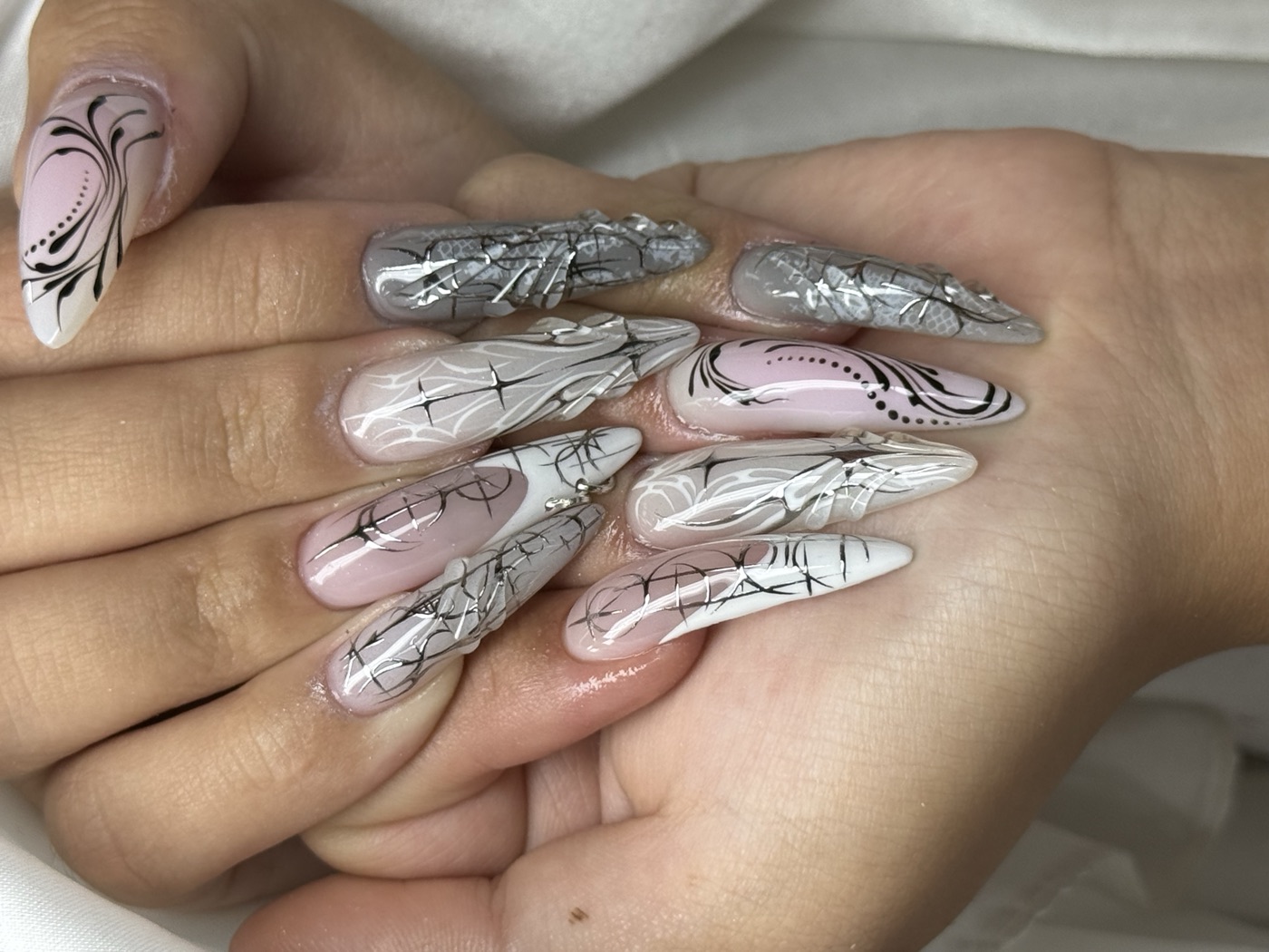 Sheer pink stiletto nails with fine black-and-white linework and silver chrome accents