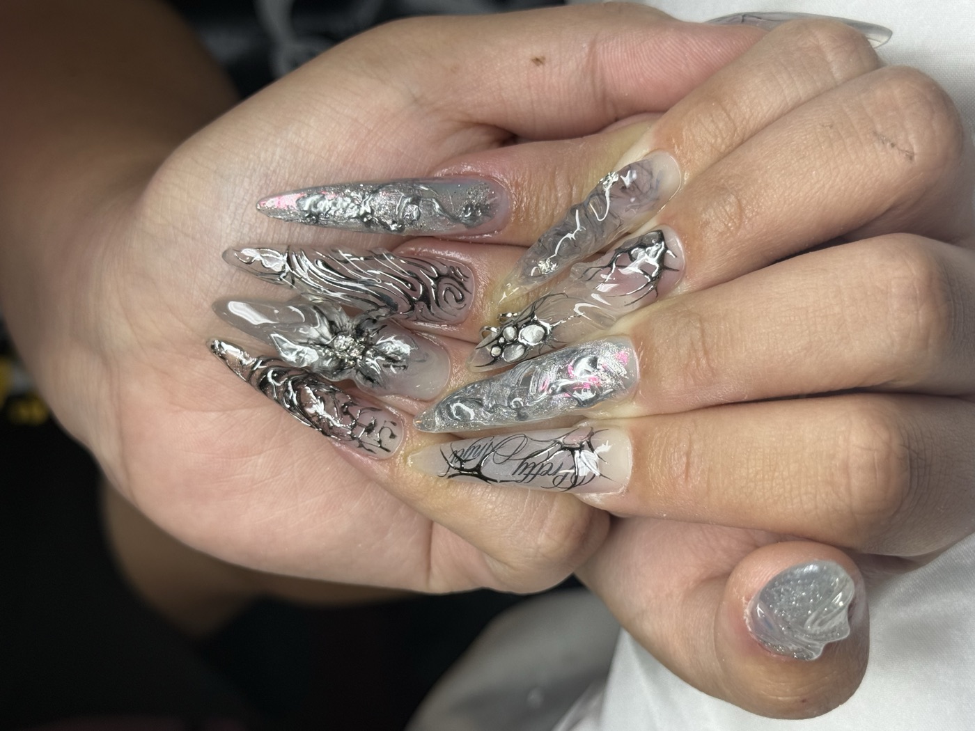 Long stiletto set in liquid silver chrome with sculpted 3D metallic florals and fine-line script